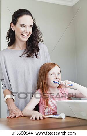 Mother watching daughter brush teeth View Large Photo Image Picture - Mother watching daughter brush teeth. Fotosearch