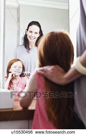 Stock Photograph - Mother watching daughter brush teeth. Fotosearch