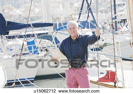 Stock Image - Older man standing on boat. Fotosearch