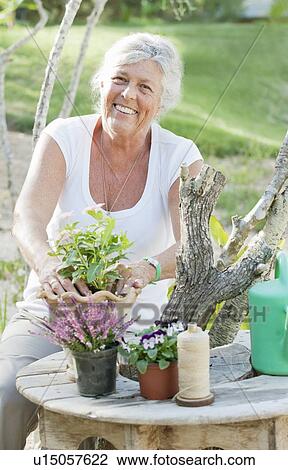 Older woman arranging flowers outdoors View Large Photo Image Stock Image - Older woman arranging flowers outdoors. Fotosearch