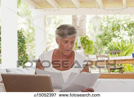 Stock Photo - Older woman paying bills on laptop. Fotosearch