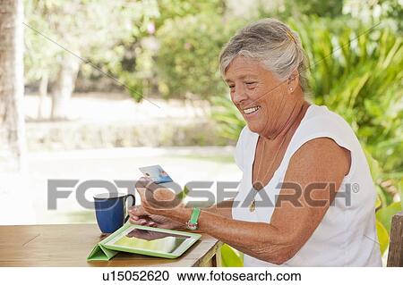 Stock Image - Older woman shopping online. Fotosearch