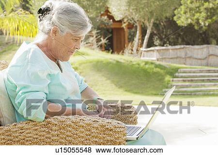 Stock Photo - Older woman using laptop outdoors. Fotosearch