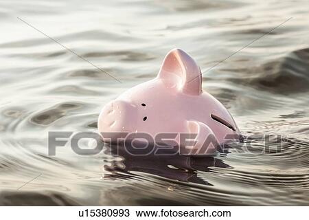 Stock Image - Piggy bank floating in water. Fotosearch