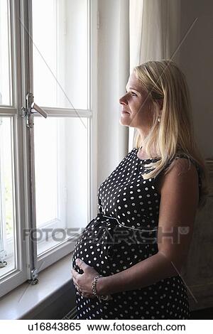 Pregnant woman smiling at window View Large Photo Image Stock Photography - Pregnant woman smiling at window. Fotosearch