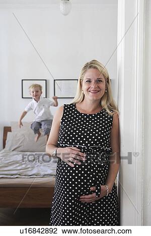 Stock Image - Pregnant woman smiling in bedroom. Fotosearch