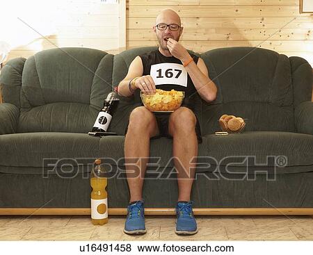 Runner eating chips on sofa View Large Photo Image Stock Photo - Runner eating chips on sofa. Fotosearch