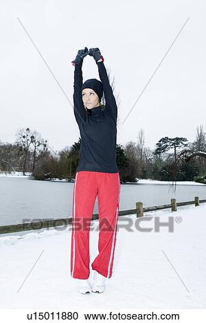 Stock Image - Runner stretching in snowy field. Fotosearch
