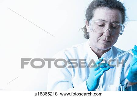 Stock Photo - Scientist dropping liquid into beaker. Fotosearch