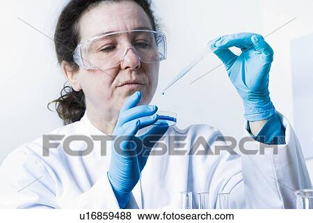 Stock Photo - Scientist dropping liquid into petri dish. Fotosearch
