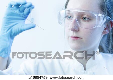 Stock Photo - Scientist examining test tube in lab. Fotosearch