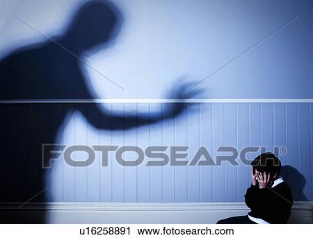 Stock Image - Shadow looming over frightened boy. Fotosearch