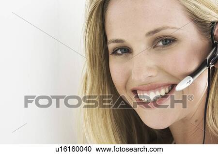 Stock Image - Smiling businesswoman wearing headset. Fotosearch