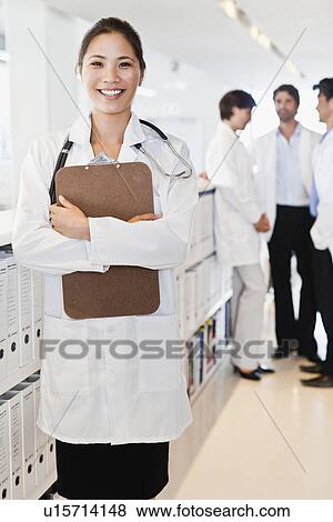 Smiling doctor holding clipboard View Large Photo Image Stock Photo - Smiling doctor holding clipboard. Fotosearch