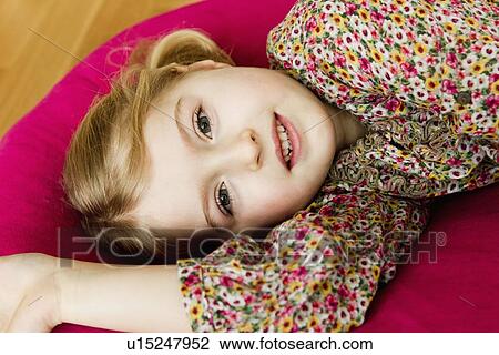 Stock Image - Smiling girl laying on pillow. Fotosearch