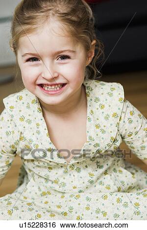 Stock Photograph - Smiling girl sitting indoors. Fotosearch