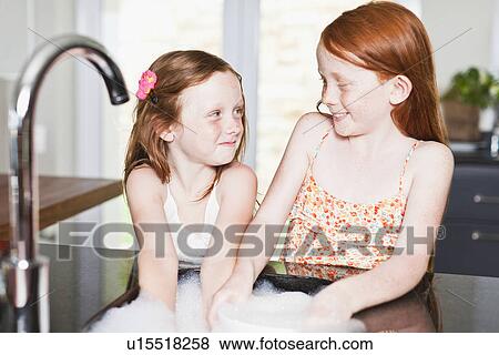 Smiling girls washing dishes in sink View Large Photo Image Stock Photo - Smiling girls washing dishes in sink. Fotosearch