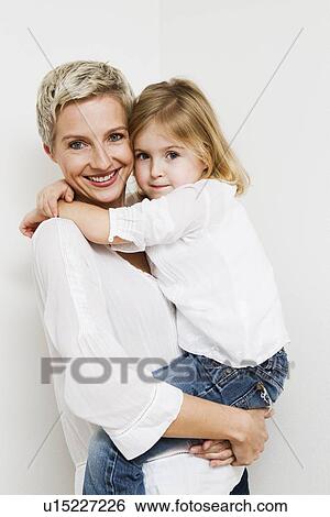 Stock Photograph - Smiling mother and daughter hugging. Fotosearch