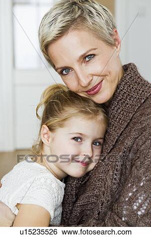 Stock Photograph - Smiling mother and daughter hugging. Fotosearch