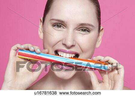 Stock Photo - Smiling woman biting candy. Fotosearch