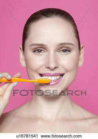 Stock Image - Smiling woman brushing her teeth. Fotosearch