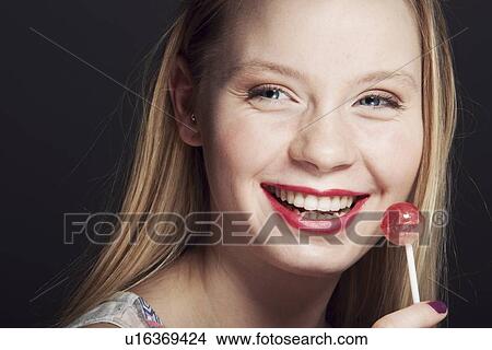 Picture - Smiling woman eating lollipop. Fotosearch