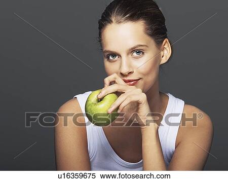 Stock Photography - Smiling woman holding apple. Fotosearch
