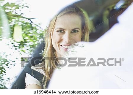 Picture - Smiling woman sitting in car. Fotosearch