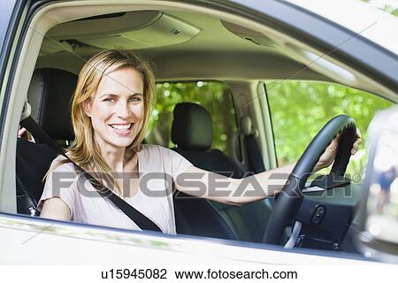 Stock Image - Smiling woman sitting in car. Fotosearch