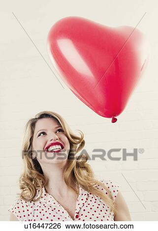 Smiling woman with heart shaped balloon View Large Photo Image Stock Photograph - Smiling woman with heart shaped balloon. Fotosearch