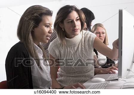 Stock Image - Teacher helping student use computer. Fotosearch