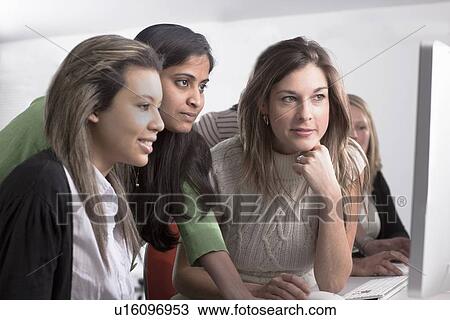 Stock Image - Teacher helping student use computer. Fotosearch
