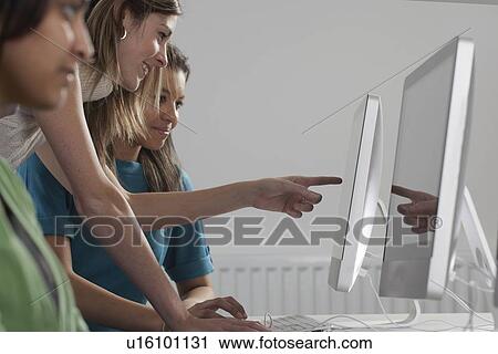 Stock Image - Teacher helping student use computer. Fotosearch