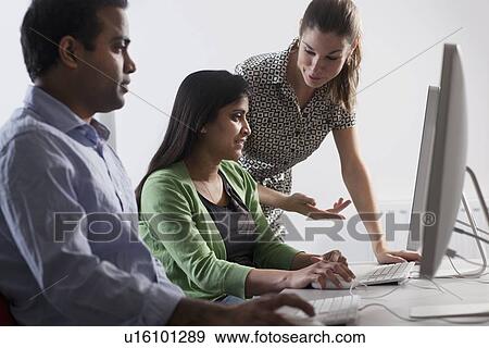 Teacher helping student use computer View Large Photo Image Stock Photo - Teacher helping student use computer. Fotosearch