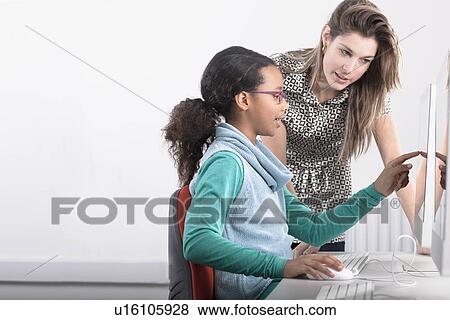 Stock Photo - Teacher helping student use computer. Fotosearch
