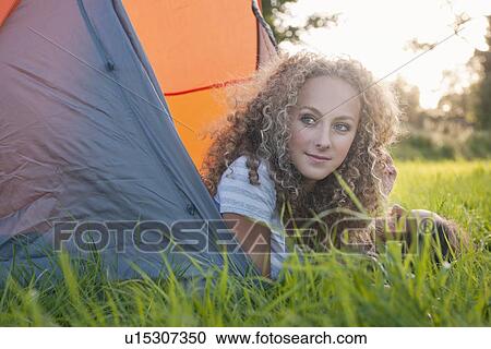 Stock Image - Teenage girl laying in tent at campsite. Fotosearch