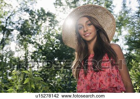 Stock Image - Teenage girl wearing straw hat outdoors. Fotosearch