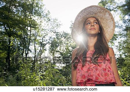 Stock Photo - Teenage girl wearing straw hat outdoors. Fotosearch