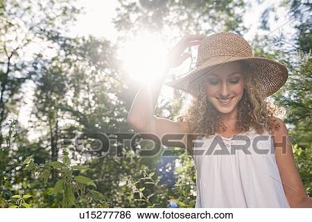 Stock Photograph - Teenage girl wearing straw hat outdoors. Fotosearch