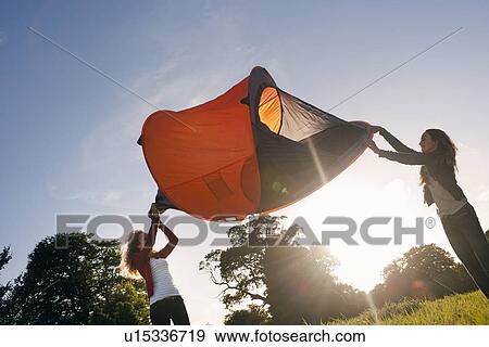 Stock Photo - Teenage girls pitching tent in field. Fotosearch