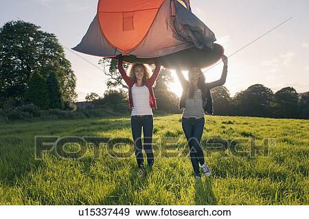 Stock Photo - Teenage girls pitching tent in field. Fotosearch