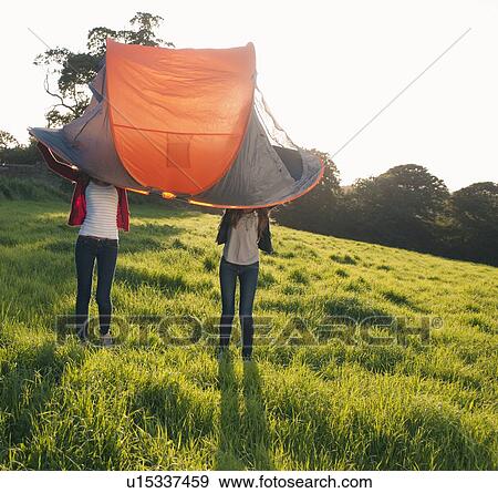 Stock Photo - Teenage girls pitching tent in field. Fotosearch