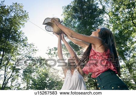 Teenage girls playing with straw hat View Large Photo Image Stock Image - Teenage girls playing with straw hat. Fotosearch