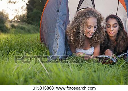 Stock Photo - Teenage girls reading in tent. Fotosearch