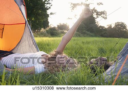 Stock Photo - Teenage girls taking picture at campsite. Fotosearch