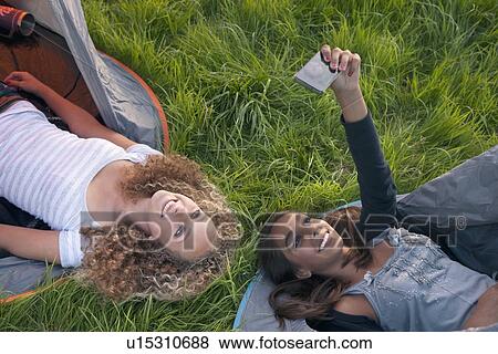 Stock Photo - Teenage girls taking picture at campsite. Fotosearch