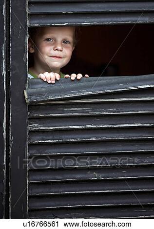 Stock Image - Toddler boy peeking out from window. Fotosearch