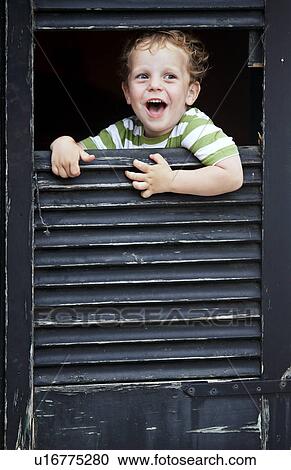 Toddler boy peeking out from window View Large Photo Image Stock Image - Toddler boy peeking out from window. Fotosearch