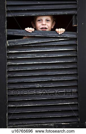 Toddler boy peeking out from window View Large Photo Image Stock Photograph - Toddler boy peeking out from window. Fotosearch