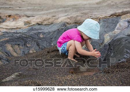 Toddler girl playing in sand on beach View Large Photo Image Stock Photo - Toddler girl playing in sand on beach. Fotosearch